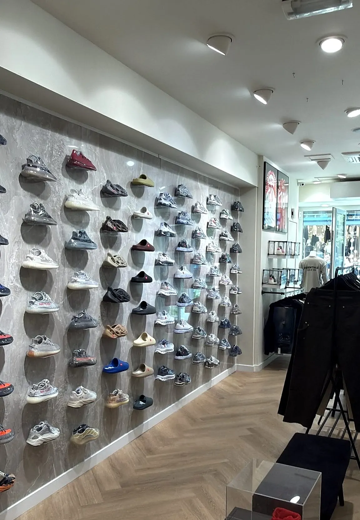 De sneakerwand in de winkel, met rechts het kledingrek